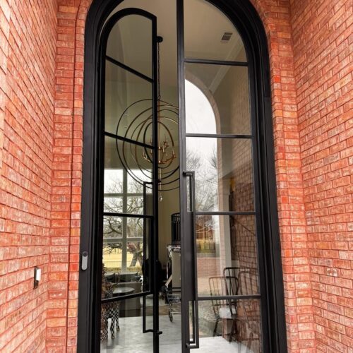 Custom double French iron door with round top and clear glass panels – exterior view