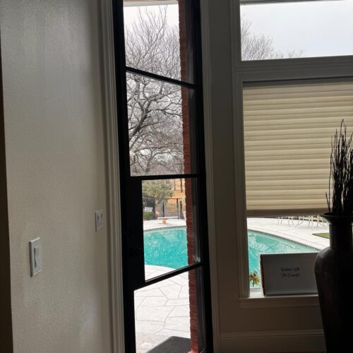 Slim black iron door with clear glass panels – interior view leading to pool patio