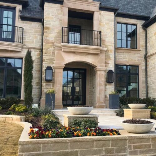 Custom double iron door with matching windows and balcony railing on stone façade home