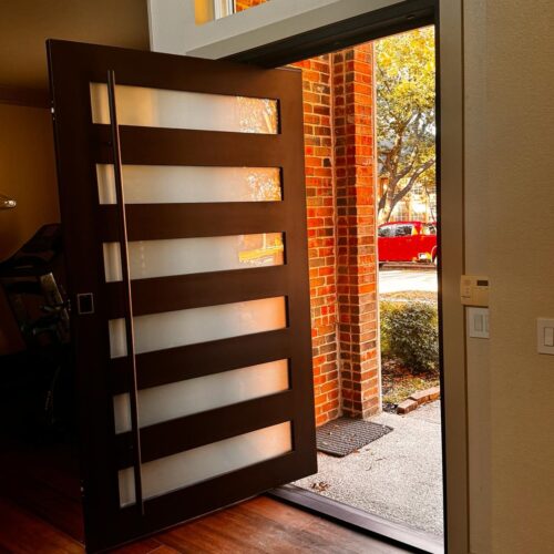 Modern pivot iron door with frosted glass panels – open view from interior